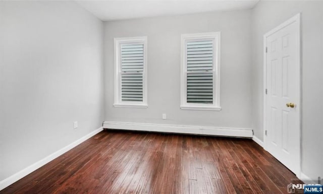 empty room with dark wood-style flooring, baseboards, and baseboard heating