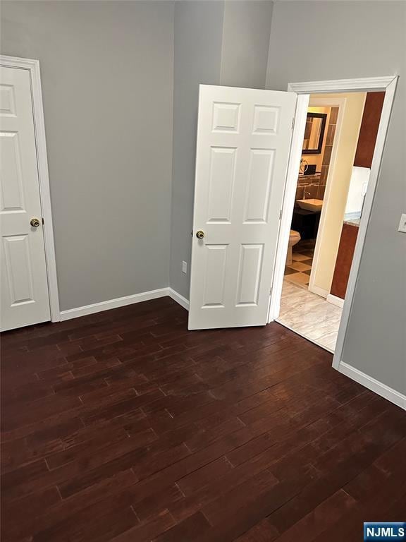 unfurnished room with dark wood-style floors and baseboards