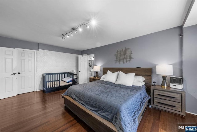 bedroom with track lighting and wood finished floors