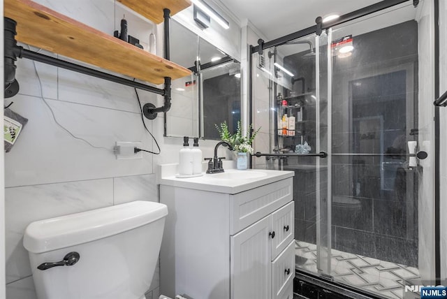 full bath with a stall shower, tile walls, vanity, and toilet