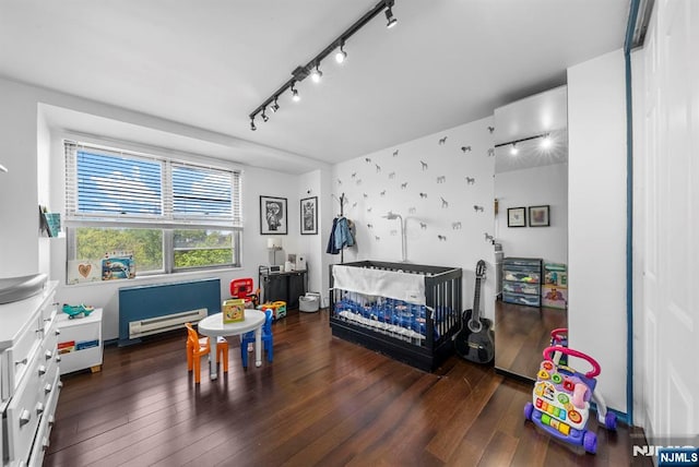 bedroom with hardwood / wood-style floors, track lighting, and a baseboard heating unit