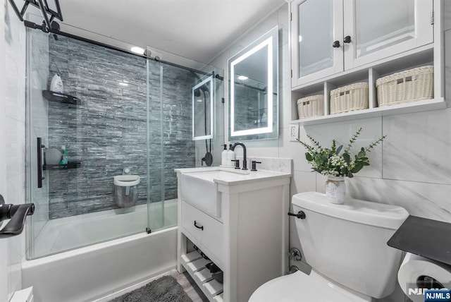bathroom featuring toilet, vanity, and combined bath / shower with glass door