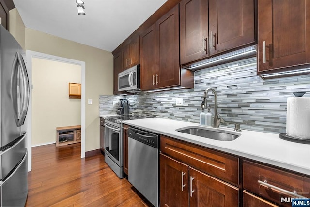 kitchen featuring dark wood-style flooring, stainless steel appliances, tasteful backsplash, and a sink