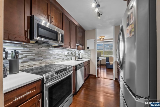 kitchen featuring a sink, light countertops, appliances with stainless steel finishes, tasteful backsplash, and dark wood-style floors