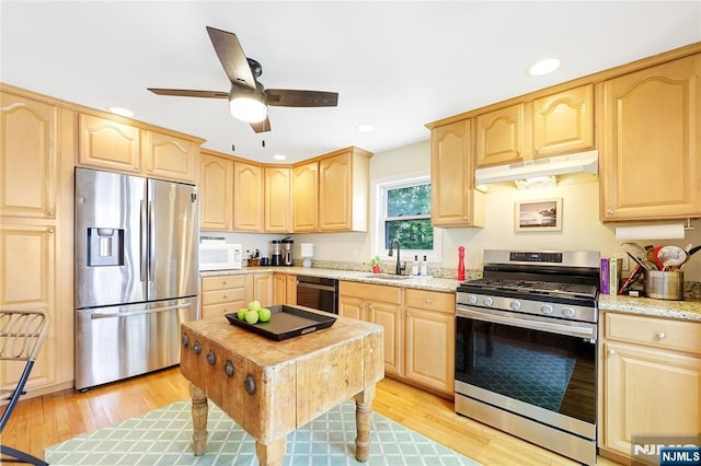 kitchen featuring under cabinet range hood, light wood finished floors, light brown cabinetry, and appliances with stainless steel finishes