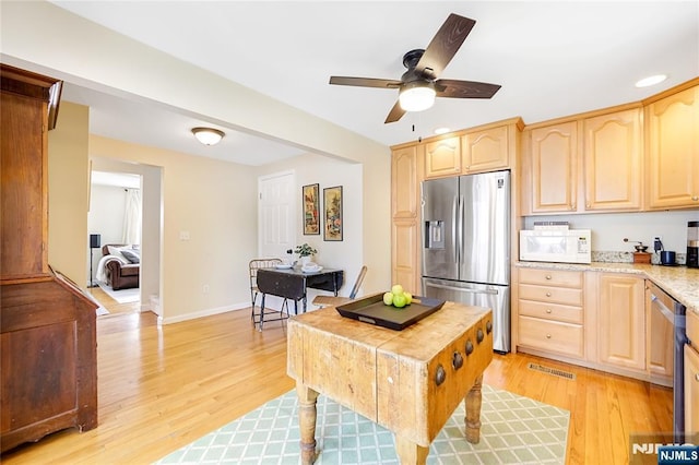 kitchen featuring light wood-type flooring, stainless steel fridge, white microwave, and light brown cabinetry