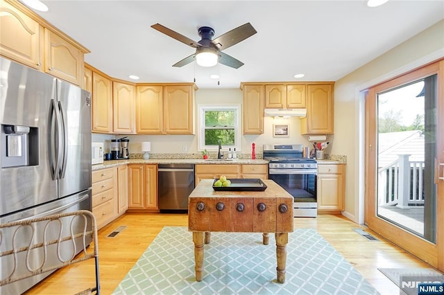 kitchen with a sink, stainless steel appliances, recessed lighting, under cabinet range hood, and light brown cabinets