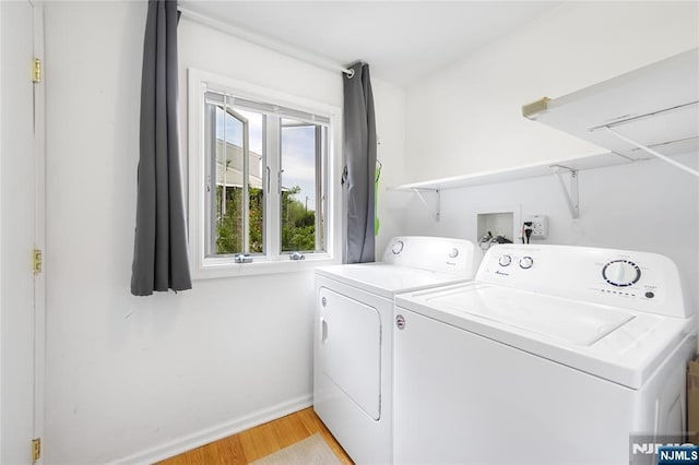 clothes washing area with separate washer and dryer, laundry area, light wood-type flooring, and baseboards