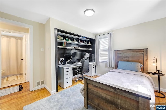 bedroom with baseboards, visible vents, and wood finished floors