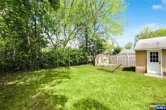 view of yard with a storage unit, fence, and an outbuilding
