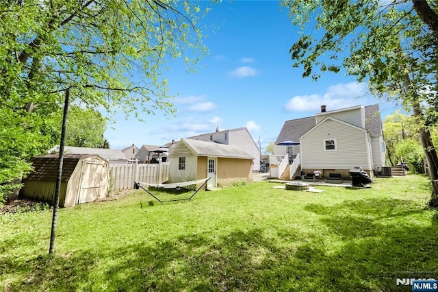 rear view of house featuring a lawn, a chimney, fence, a shed, and an outdoor structure