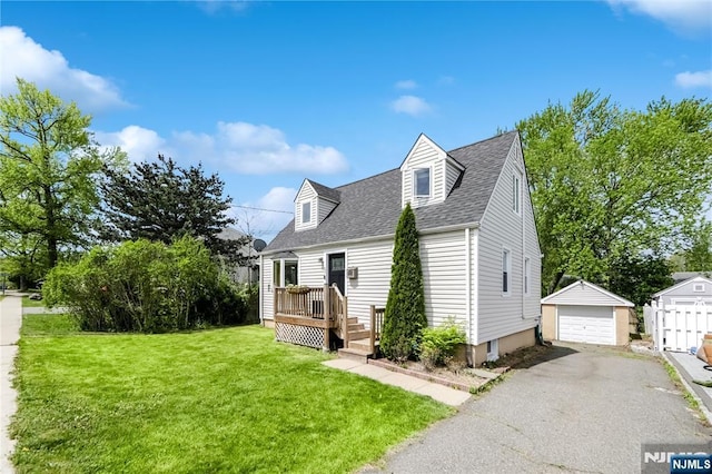 view of front facade featuring aphalt driveway, an outdoor structure, a garage, a front yard, and a shingled roof