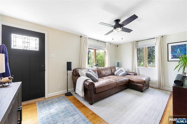 living area with ceiling fan, baseboards, and light wood-type flooring
