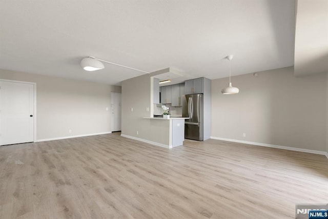 unfurnished living room with light wood finished floors and baseboards