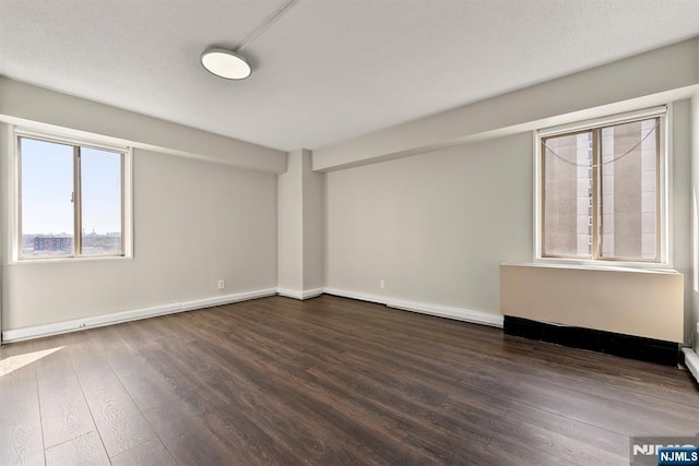 empty room featuring baseboards and dark wood finished floors
