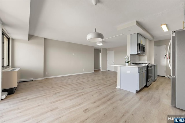 kitchen featuring light wood-style flooring, gray cabinetry, open floor plan, light countertops, and appliances with stainless steel finishes