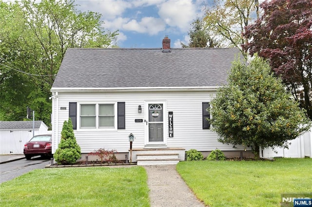 cape cod-style house featuring a chimney, roof with shingles, and a front lawn