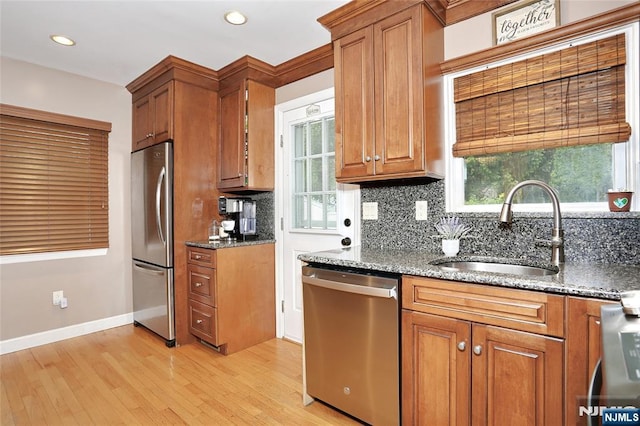 kitchen featuring stainless steel appliances, a sink, tasteful backsplash, brown cabinetry, and recessed lighting