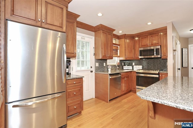 kitchen with appliances with stainless steel finishes, light wood finished floors, decorative backsplash, and recessed lighting