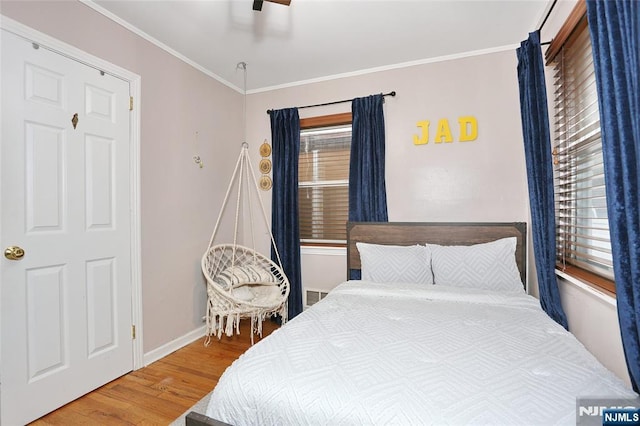 bedroom with wood finished floors, baseboards, ornamental molding, and a ceiling fan