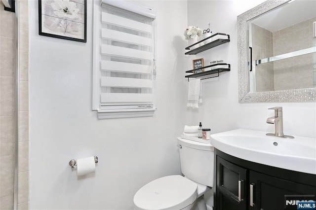 full bath with toilet, tiled shower, and vanity