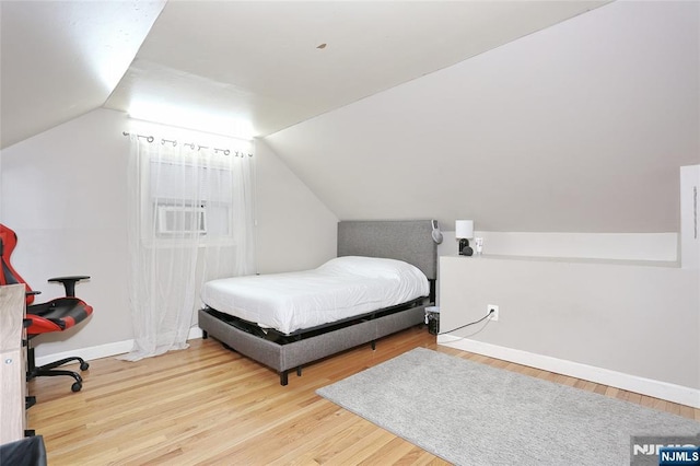 bedroom with wood finished floors, lofted ceiling, and baseboards