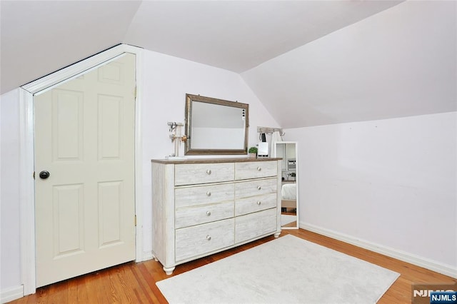 bedroom with lofted ceiling, wood finished floors, and baseboards