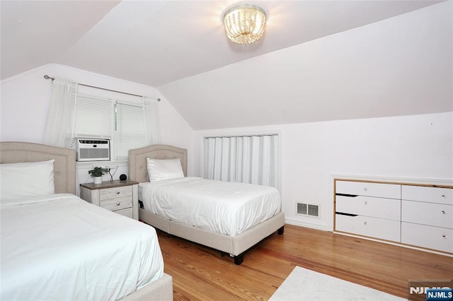 bedroom with wood finished floors, vaulted ceiling, and cooling unit