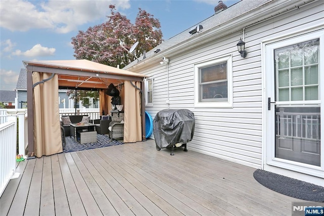 wooden terrace featuring a gazebo, an outdoor living space, and grilling area