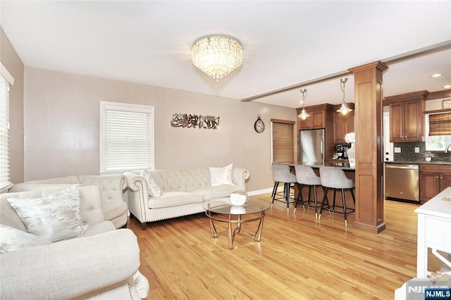 living area with light wood-style floors, a chandelier, and baseboards