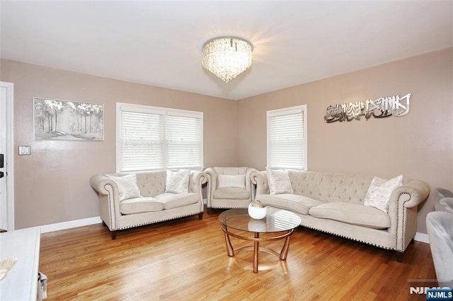 living room with healthy amount of natural light, light wood finished floors, a chandelier, and baseboards