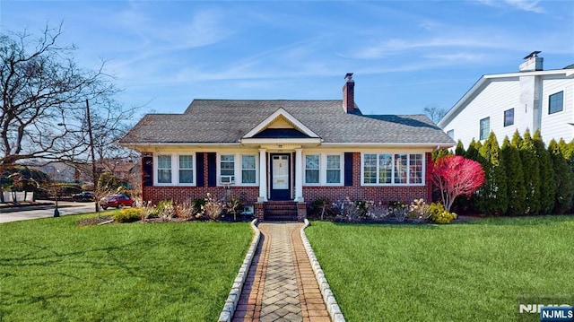 bungalow-style house with a front lawn, brick siding, a chimney, and a shingled roof