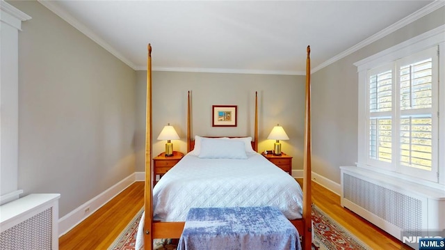 bedroom with radiator heating unit, wood finished floors, baseboards, and crown molding