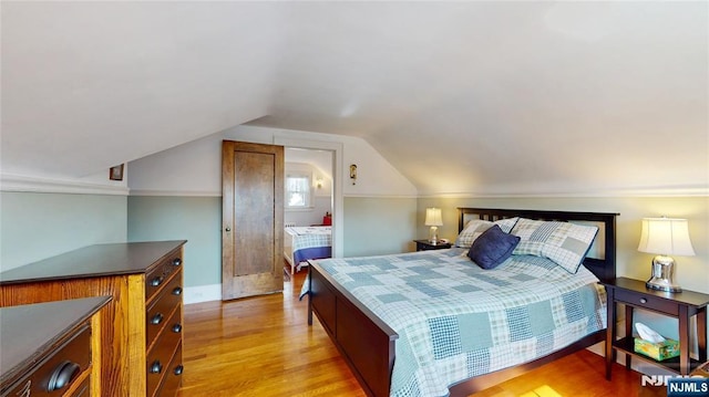 bedroom featuring light wood-type flooring, vaulted ceiling, and baseboards