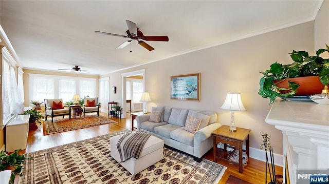 living area with ceiling fan, ornamental molding, wood finished floors, and baseboards