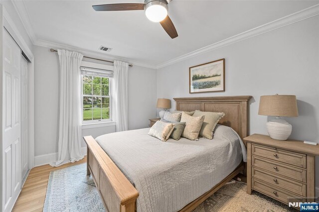 bedroom featuring crown molding, light wood-style floors, baseboards, a ceiling fan, and a closet