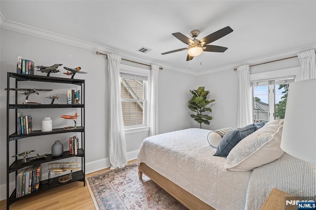 bedroom featuring light wood-style flooring, ornamental molding, multiple windows, baseboards, and ceiling fan