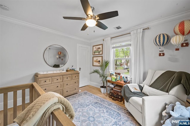 bedroom with ornamental molding, light wood-style floors, baseboards, and ceiling fan