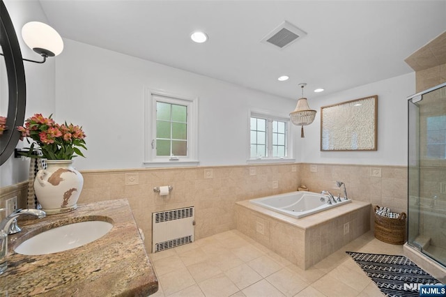 bathroom with radiator heating unit, tile patterned flooring, a shower stall, tile walls, and wainscoting