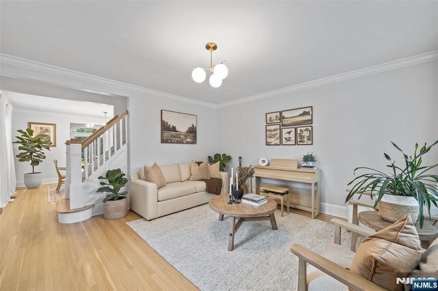 living area featuring a chandelier, light wood finished floors, ornamental molding, stairs, and baseboards