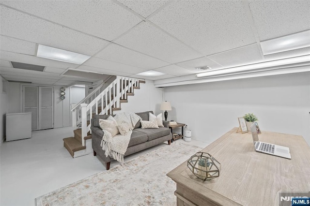 living area with stairway, a paneled ceiling, and finished concrete floors