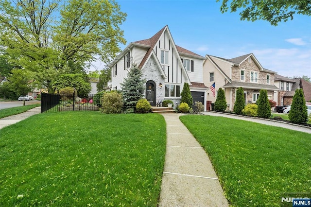 tudor home with a garage, stone siding, and driveway