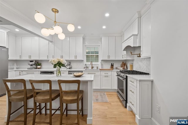 kitchen with appliances with stainless steel finishes, a sink, light countertops, white cabinetry, and recessed lighting