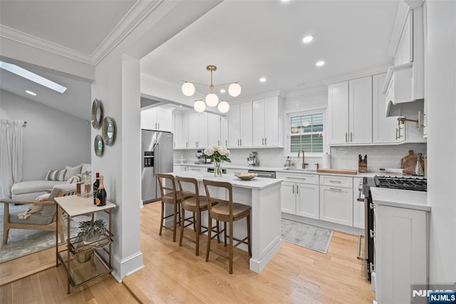 kitchen with high end appliances, crown molding, white cabinetry, a center island, and a breakfast bar
