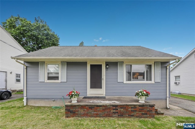 bungalow-style house featuring roof with shingles and a front yard