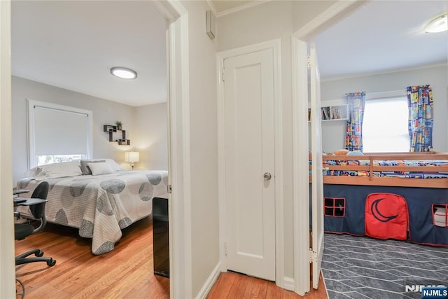 bedroom with wood finished floors, crown molding, and baseboards