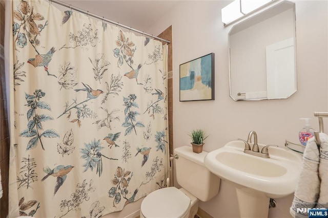 bathroom with a sink, curtained shower, and toilet