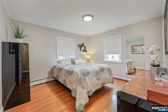 bedroom featuring a baseboard radiator, light wood-style floors, and multiple windows