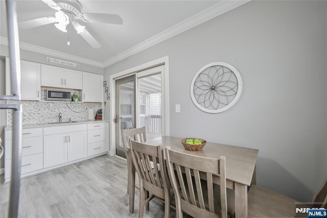 dining area with ornamental molding, ceiling fan, and light wood-style flooring