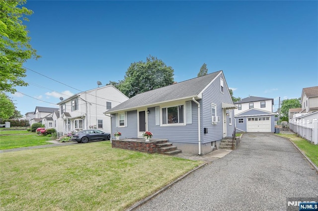 view of front of property with a detached garage, a front lawn, asphalt driveway, and a residential view